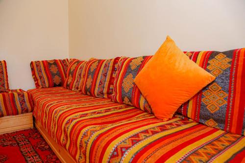 a colorful couch with an orange pillow on it at Wadahab House An Ideal Retreat for Families and Friends in Er Rachidia