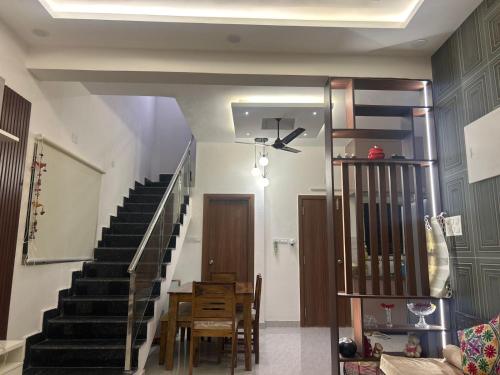 a living room with a staircase and a table and chairs at Aayushman Luxury Homes in Sarjāpur