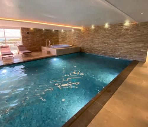 a swimming pool in a house with a bathtub at Porthminster View Luxury Sea Views Balcony, Parking, Pool, Spa & Gym in St Ives