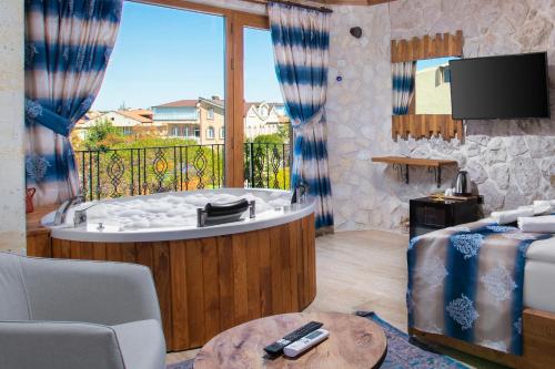 a living room with a tub with a balcony at Cappadocia Fiesta Stone House in Uchisar