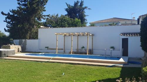 a swimming pool in a yard next to a white building at Casa El Veranito in Chiclana de la Frontera