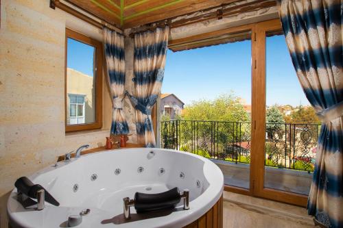 a bath tub in a bathroom with a large window at Cappadocia Fiesta Stone House in Uchisar