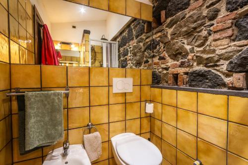 a bathroom with a toilet and a stone wall at Villa Felice in Giardini Naxos