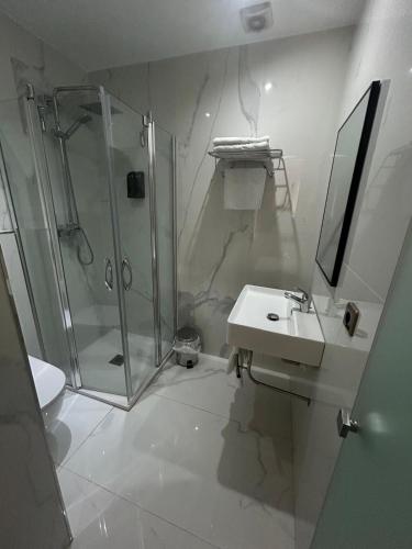 a white bathroom with a shower and a sink at Hostal Plaza in Marmolejo