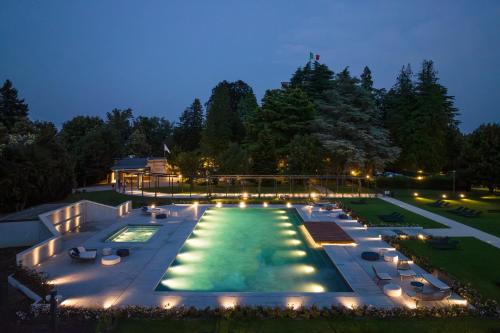 a large pool with lights in a backyard at night at Palace Grand Hotel Varese in Varese
