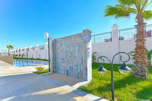 a villa with a gate and a palm tree at Sıfır Muhteşem Havuzlu Aileye Özel 1e1 Rezidans in Alanya
