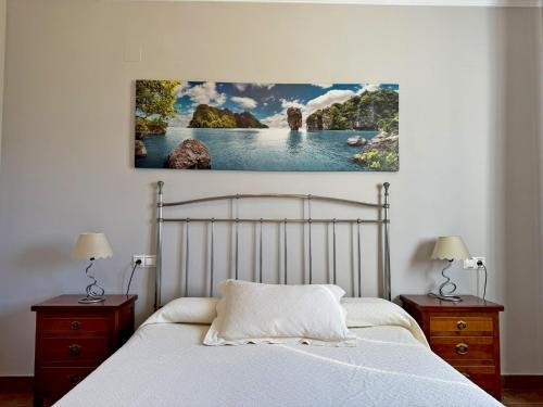 a bedroom with a white bed with two night stands and two lamps at El Bosque del Duende - Ole Solutions in Arcos de la Frontera