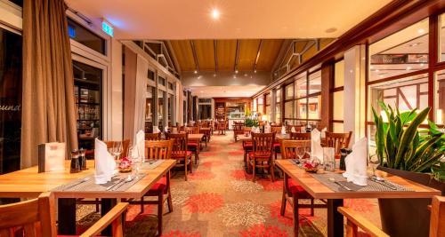 a restaurant with wooden tables and chairs and windows at PLAZA INN Goslar in Goslar