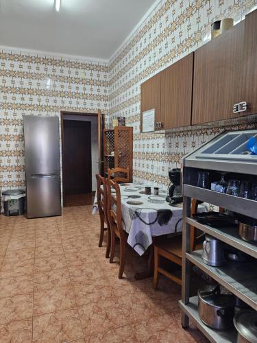 a kitchen with a table and a stainless steel refrigerator at Aguarela Tavira in Tavira