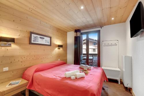 a bedroom with a red bed and a television at l'Ours Bleu B33 ski -in ski -out - Happy Rentals in Vallorcine