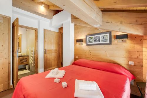 a bedroom with a red bed with two towels on it at l'Ours Bleu B33 ski -in ski -out - Happy Rentals in Vallorcine
