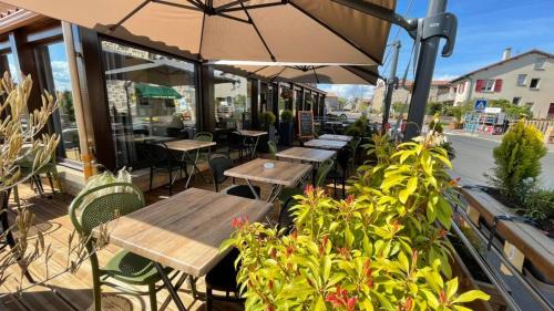un patio extérieur avec tables, chaises et plantes dans l'établissement Auberge du Couvige, à Le Bouchet-Saint-Nicolas