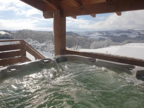 une baignoire jacuzzi sur une terrasse couverte avec de la neige au sol dans l'établissement Rouet Nature, à Tréban