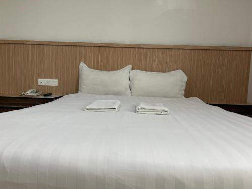 a large white bed with two towels on it at Mint Hotel in Labuan