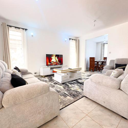 a living room with two couches and a tv at Bertess in Kikuyu