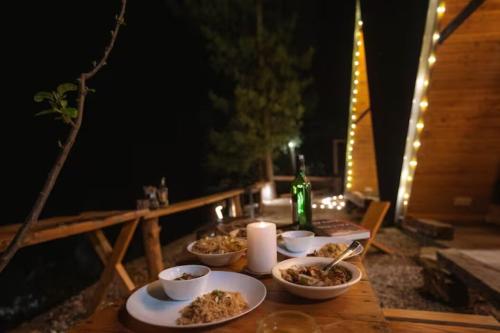 a table with bowls of food and a bottle of wine at Vibrant A-Frame In The Valley By Bastiat Stays in Mandi