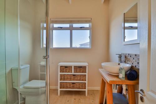 ベティーズ・ベイにあるTidesの洗面台とガラスのシャワーを備えたバスルーム