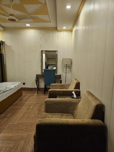 a room with three couches and a desk and a piano at booking at lodges in Lahore