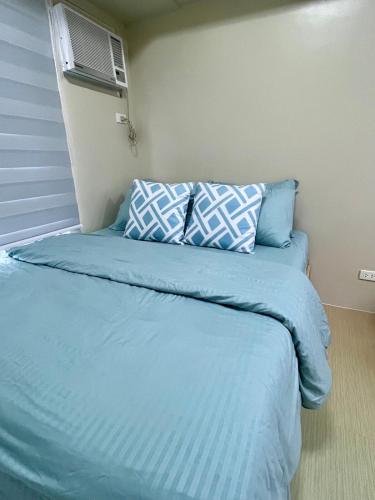 a bed with blue sheets and pillows in a room at The Charmed Place Iloilo in Iloilo City