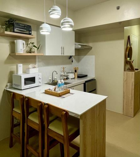 a kitchen with a counter with chairs and a microwave at The Charmed Place Iloilo in Iloilo City