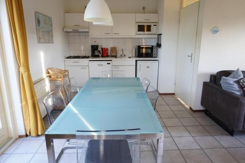 a kitchen with a blue table and a couch at Kustverhuur, Park Schoneveld, Zeemeeuw 164 in Breskens