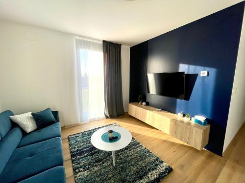 Una sala de estar con un sofá azul y un televisor. en Urban CARTA I apartment, en Liptovský Mikuláš