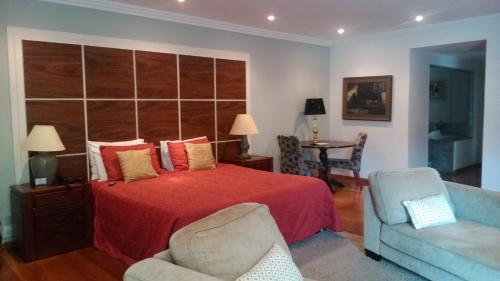 a bedroom with a bed and a couch and a chair at Pousada Quinta dos Pássaros Itaipava in Itaipava