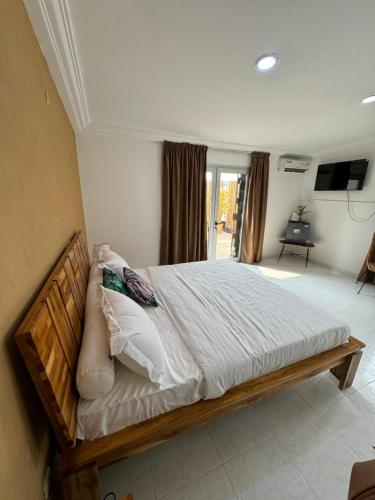 a bedroom with a large bed with white sheets and pillows at Chambre La Villa Kalanga in Abidjan