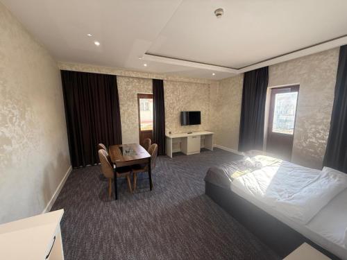 a hotel room with a bed and a table and a desk at Black Mont İnn Hotel in Baku
