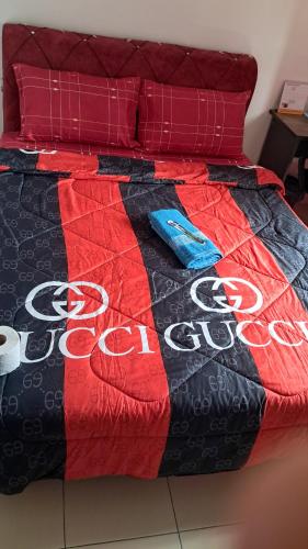 a bed with a coca cola quilt on it at The Red Room Alanis Residence in Sepang