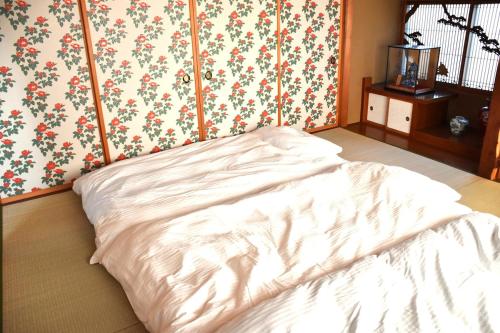 a white bed in a room with floral wallpaper at Traditional Japanese House -Near Matsumoto Castle- in Matsumoto