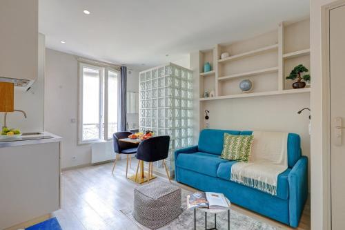 un salon avec un canapé bleu et une table dans l'établissement BnBNook - Studio - Eiffel Tower & Les Invalides, à Paris