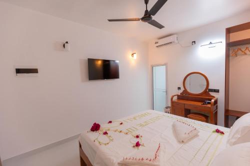 a white bedroom with a bed and a mirror at Rangali thoddoo Maldives in Thoddoo