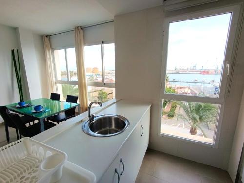 a kitchen with a sink and a large window at Apartamentos Marina Suites in Grao de Castellón