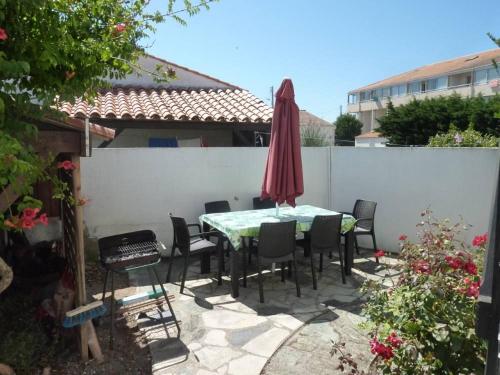 un patio avec une table, des chaises et un parasol dans l'établissement Charmante maison vendéenne avec jardin et océan à 200m, à Saint-Hilaire-de-Riez