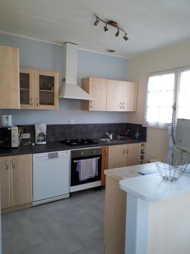 La cuisine est équipée d'appareils électroménagers blancs et de plaques de cuisson blanches. dans l'établissement Charmante maison vendéenne avec jardin et océan à 200m, à Saint-Hilaire-de-Riez