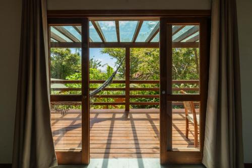 an open door to a deck with trees at Coração da Terra Praia do Rosa in Praia do Rosa