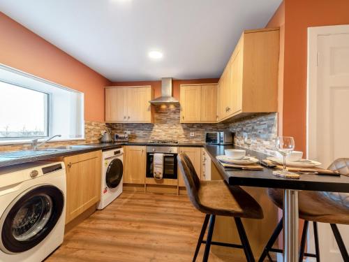 eine Küche mit Holzschränken und einem Tisch mit Stühlen in der Unterkunft 2 Bed in Falkirk 95833 in Bonnybridge