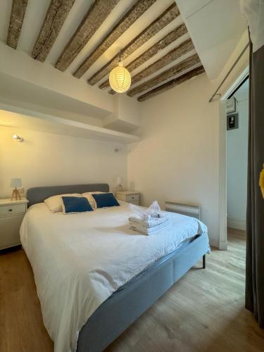 une chambre avec un grand lit blanc avec des oreillers bleus dans l'établissement Neptune, à Caen