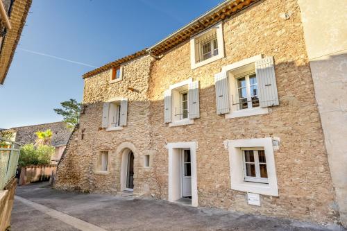 un grand bâtiment en briques avec des fenêtres blanches à volets dans l'établissement Chez Marius, à Bédoin