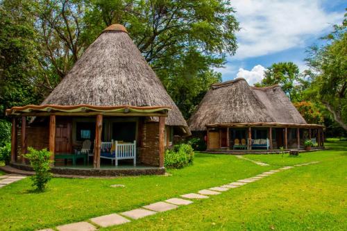 two small houses with thatched roofs in a yard at Rusinga Island Lodge in Mbita