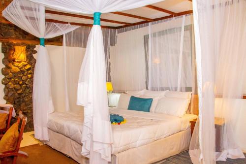 a bedroom with a white bed with a canopy at Rusinga Island Lodge in Mbita