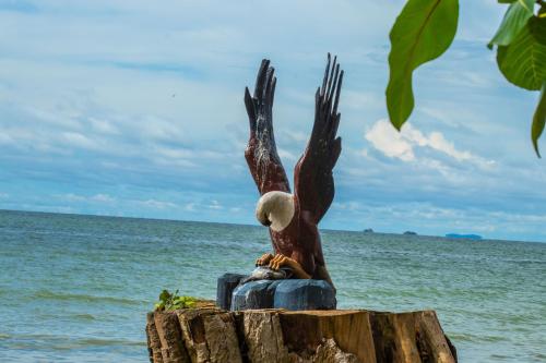 a statue of an eagle sitting on a stump near the ocean at Rusinga Island Lodge in Mbita