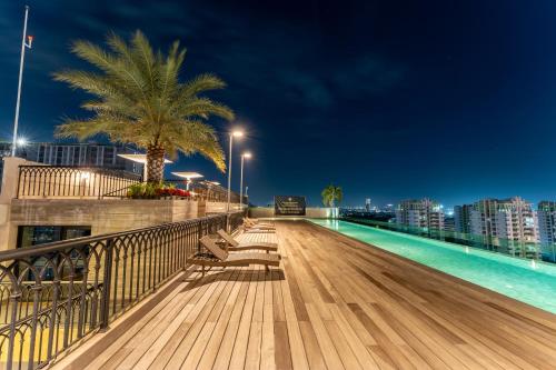 a boardwalk with benches and a swimming pool at night at The Skye Phnom Penh Hotel & Apartments in Phnom Penh