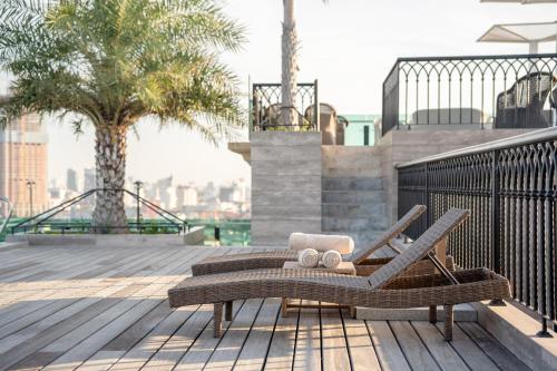 a rattan chair on a deck with a view of the city at The Skye Phnom Penh Hotel & Apartments in Phnom Penh