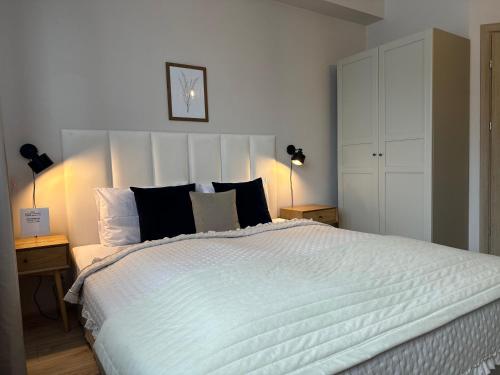 a bedroom with a large white bed with black pillows at APARTAMENTY LAVENDERIA z widokiem na Górę Parkową, blisko centrum in Kudowa-Zdrój