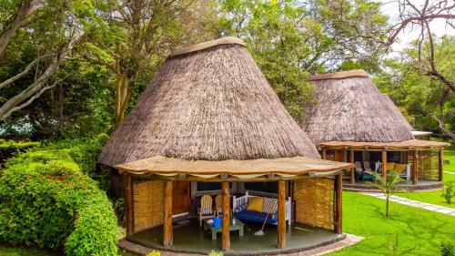 a gazebo with a thatched roof in a garden at Rusinga Island Lodge in Mbita