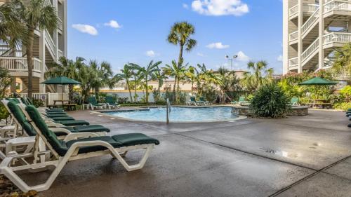 a swimming pool with chaise lounge chairs and a resort at Heated Pool Beach View Beachside Haven Balcony in Galveston