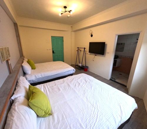 a room with two beds and a television in it at 綠島玉米-潛水住宿 Diveholix Homestay in Green Island