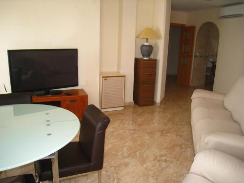 a living room with a couch and a tv and a table at Playa Los Locos - Coloso in Torrevieja